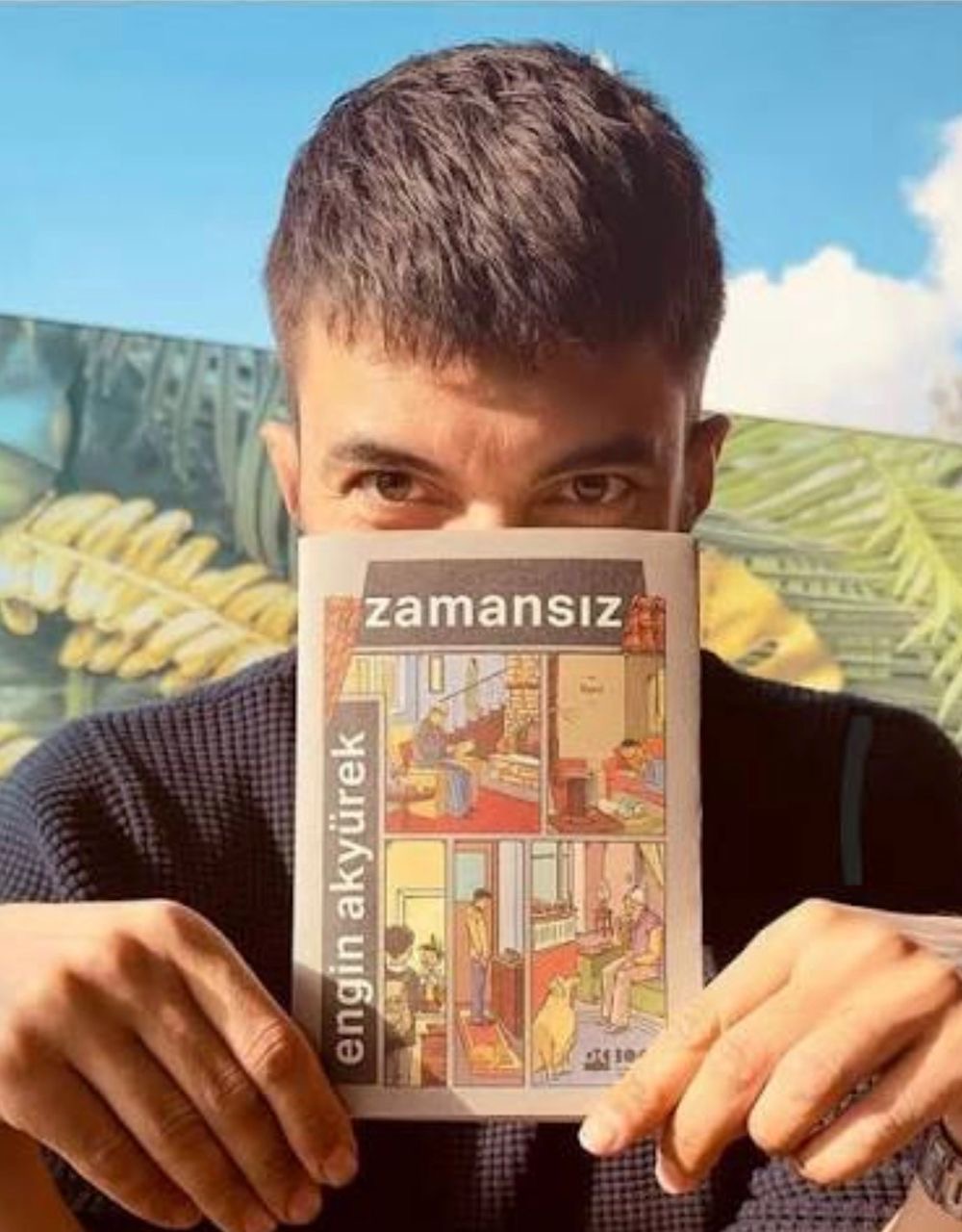 Engin Akyürek holding his book Zamansız outdoors
