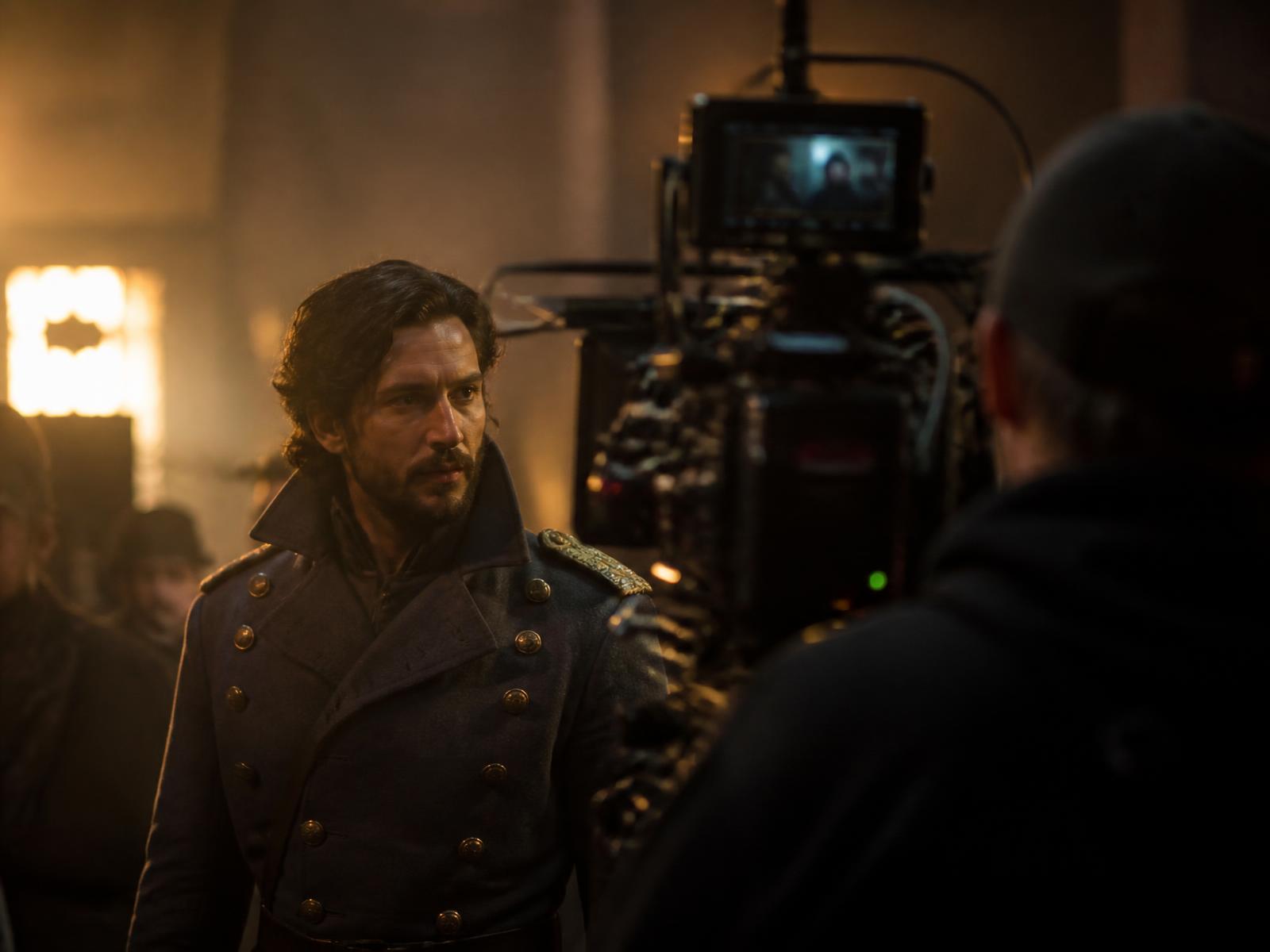 Engin Akyürek on a film set in period costume under warm lights