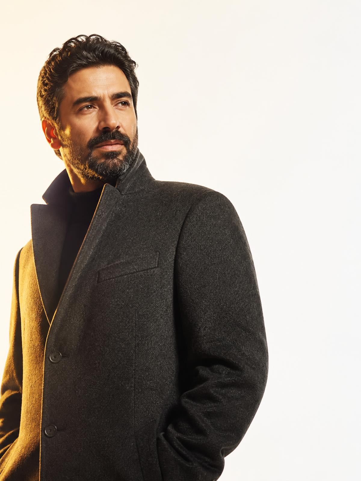 Engin Akyürek in a black overcoat under golden rim light
